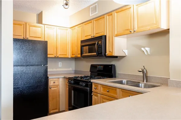 a kitchen with stainless steel appliances granite countertop a refrigerator a stove top oven a sink and dishwasher