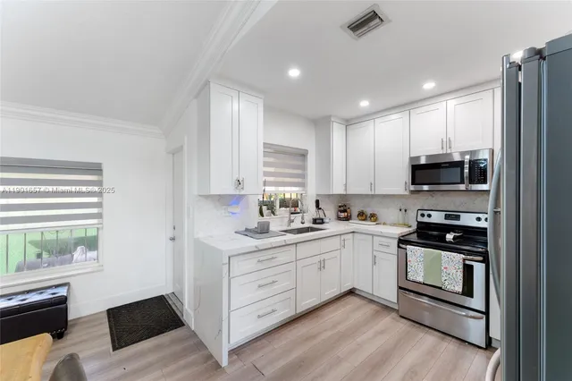 a kitchen with stainless steel appliances granite countertop a refrigerator stove sink and cabinets