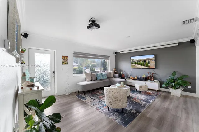a living room with furniture a flat screen tv and a floor to ceiling window