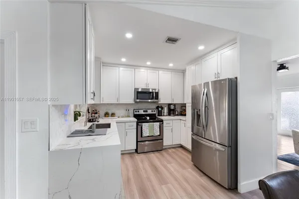 a kitchen with stainless steel appliances granite countertop a stove a sink and a refrigerator