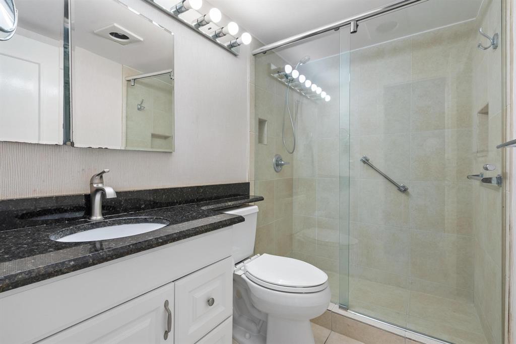 4036 Cornwall East, Unit 4036 Boca Raton, FL 33434 - Photo 12 of 30 a bathroom with a granite countertop sink a toilet and shower