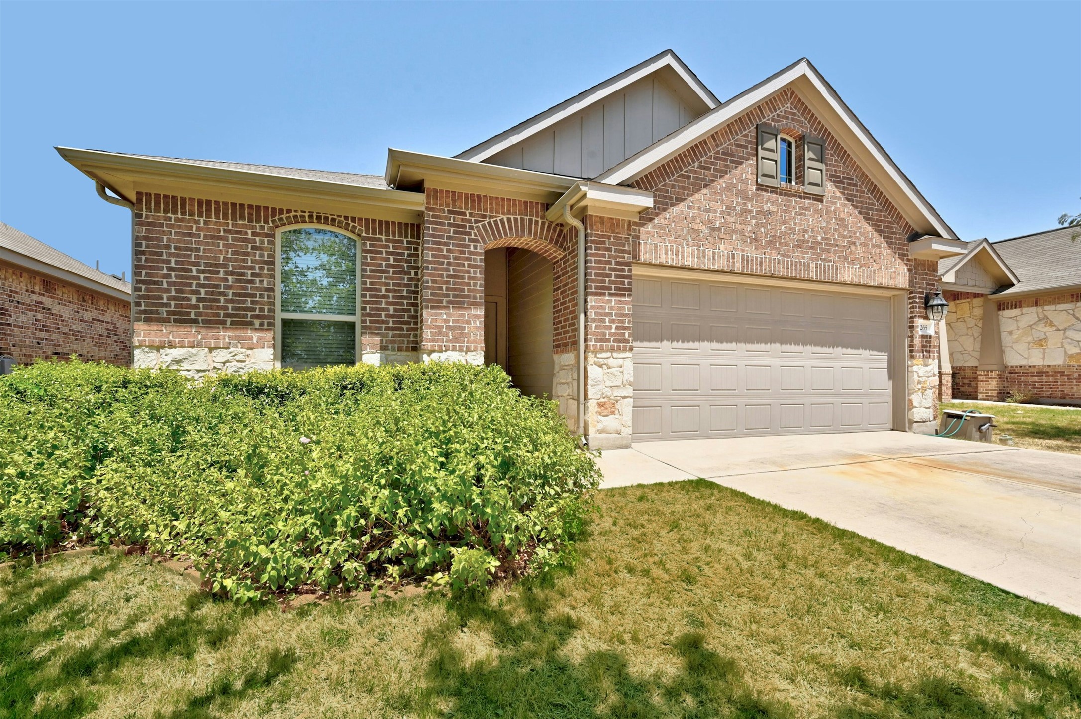 265 Shale Circle Buda, TX 78610 - Photo 1 of 1 Ranch-style house featuring concrete driveway, brick siding, board and batten siding, and an attached garage