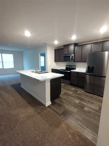 a kitchen with stainless steel appliances granite countertop a sink a stove and a refrigerator