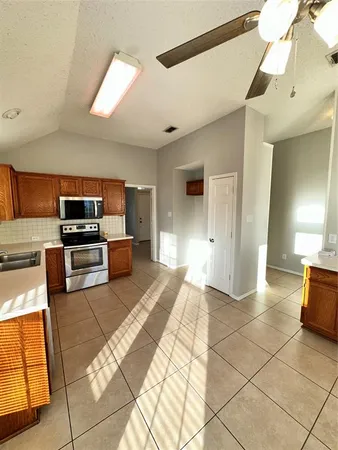 a view of a electric appliances in kitchen and empty room with wooden floor