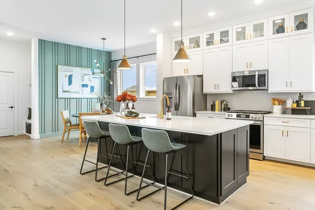 a kitchen with stainless steel appliances kitchen island a table chairs and a refrigerator