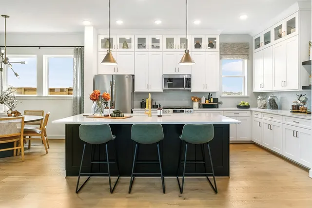 a kitchen with stainless steel appliances granite countertop a table chairs sink and window
