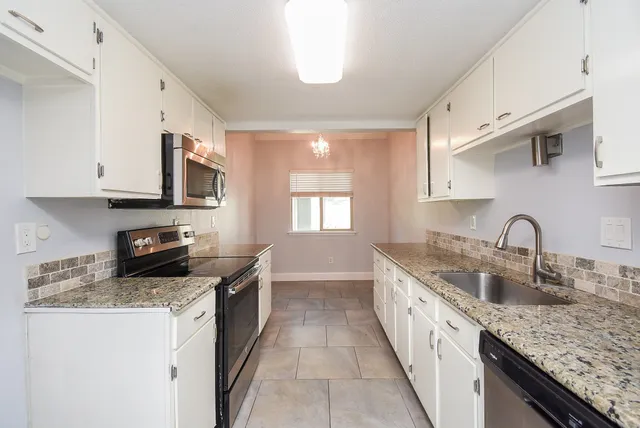 a kitchen with stainless steel appliances granite countertop a sink stove and cabinets