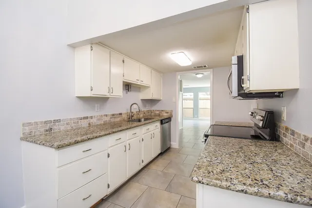 a large kitchen with granite countertop a sink and dishwasher a stove with wooden floor