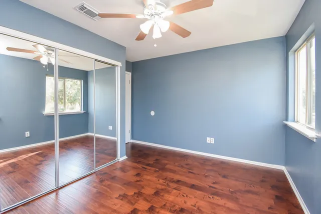 a view of an empty room with window and wooden floor