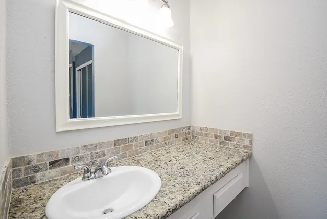 a bathroom with a granite countertop sink and a mirror