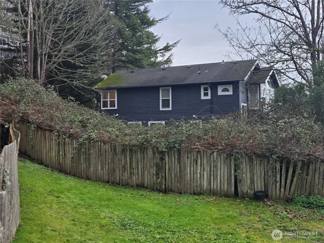 a view of a brick house next to a yard with large trees