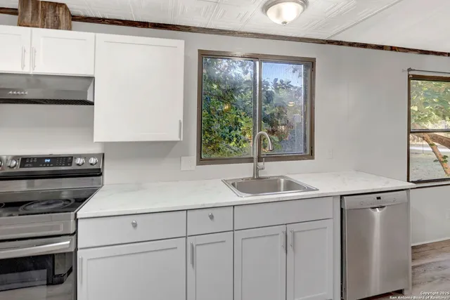 a kitchen with granite countertop a refrigerator and a stove top oven
