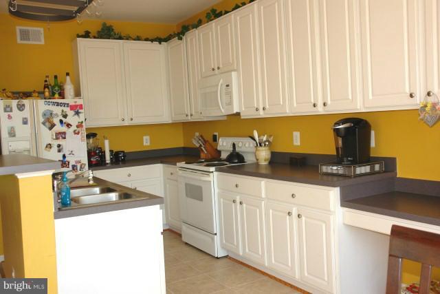 43191 Riders Square Broadlands, VA 20148 - Photo 18 of 21 a kitchen with stainless steel appliances granite countertop a sink a stove and white cabinets