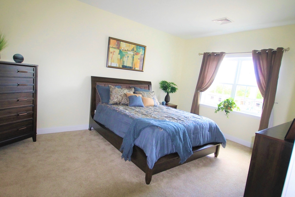 2 Regency Village Way, Unit 208 Merrimac, MA 01860 - Photo 18 of 19 a spacious bedroom with a bed and a window