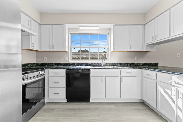 a kitchen with granite countertop cabinets stainless steel appliances a sink and a window