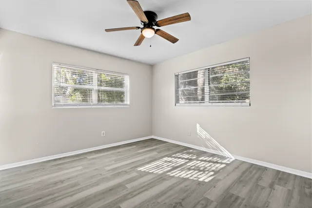 a view of empty room with wooden floor and fan