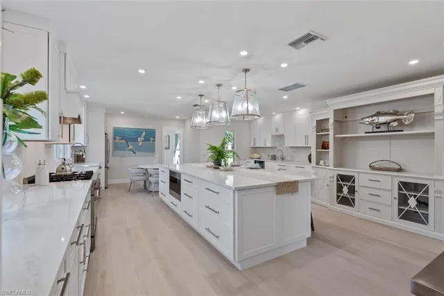 a large white kitchen with a large counter top appliances and cabinets