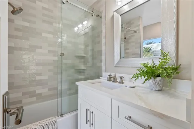 a bathroom with a sink a mirror a potted plant and a shower