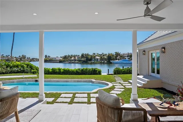 a view of a patio with lawn chairs floor to ceiling window and an outdoor kitchen