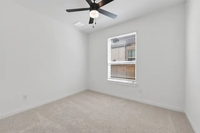 an empty room with a window and a fan