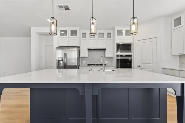 a kitchen with stainless steel appliances a sink a stove a refrigerator and cabinets