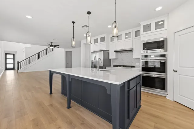 a kitchen with stainless steel appliances granite countertop a sink a stove and a wooden floors