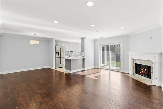 a view of an empty room with wooden floor fireplace and a window