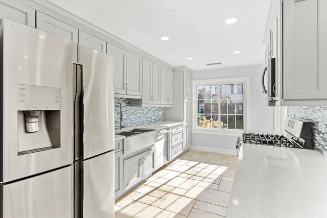 a kitchen with granite countertop a refrigerator and a stove top oven