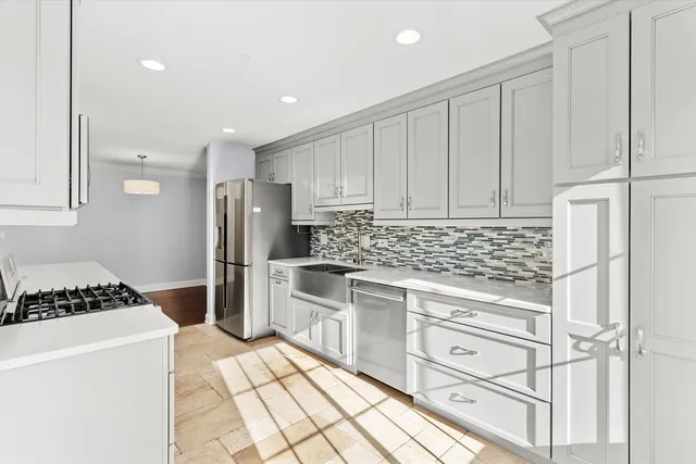 a kitchen with white cabinets and stainless steel appliances