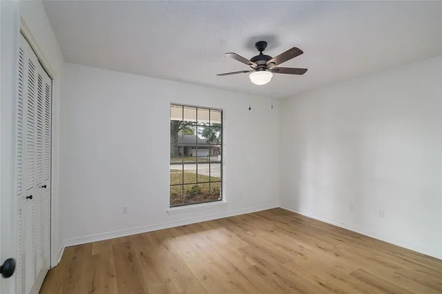 a view of empty room with wooden floor and fan