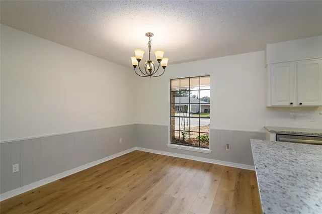 an empty room with wooden floor cabinet and windows