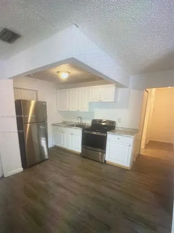 a kitchen with stainless steel appliances wooden floor and view living room