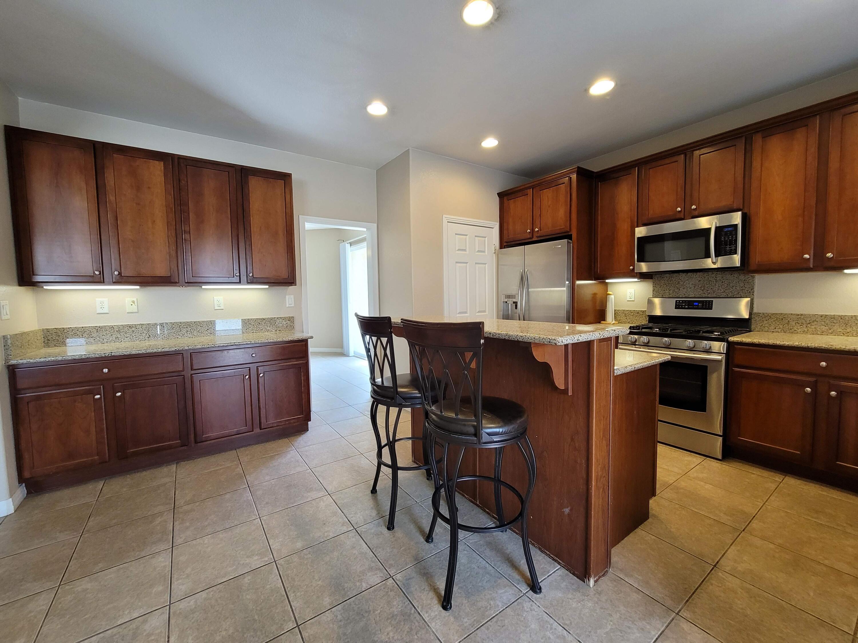 84476 Ruebens Way Coachella, CA 92236 - Photo 11 of 47 a kitchen with a sink a microwave and wooden cabinets