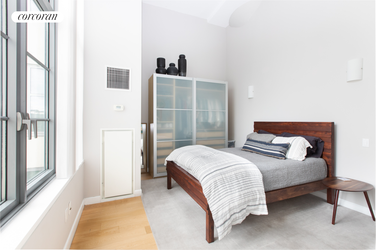 27-28 Thomson Avenue, Unit 228 Queens, NY 11101 - Photo 4 of 17 a bedroom with bed and a night stand