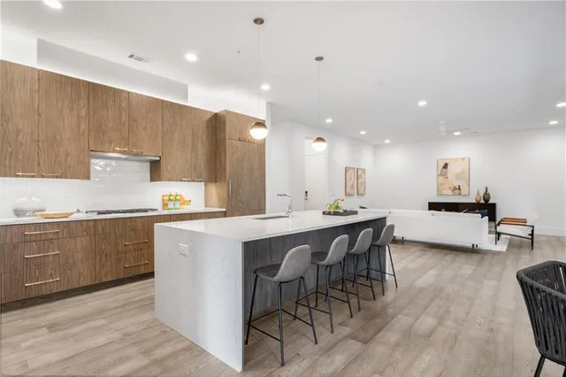 a kitchen with stainless steel appliances kitchen island granite countertop a table chairs sink and cabinets