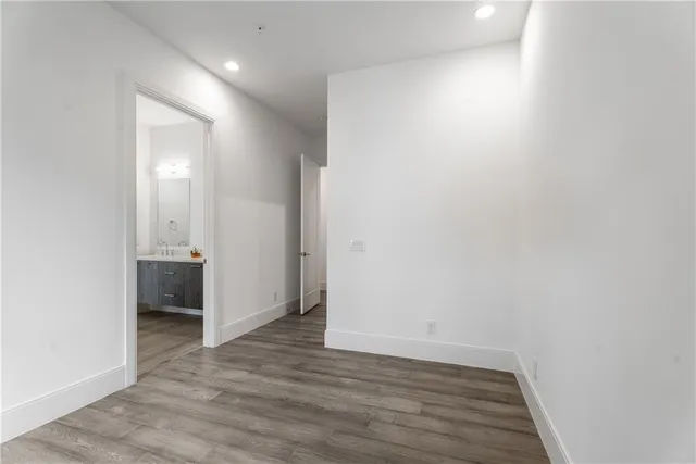 a view of an empty room with wooden floor and a bathroom