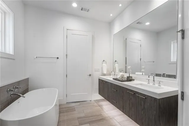 a bathroom with a double vanity sink and mirror with bathtub