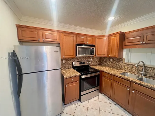 a kitchen with stainless steel appliances granite countertop a refrigerator sink and stove