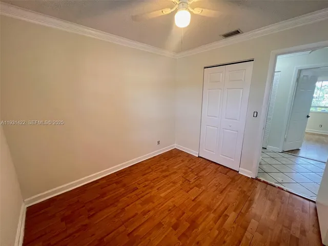 a view of an empty room with wooden floor and a fan