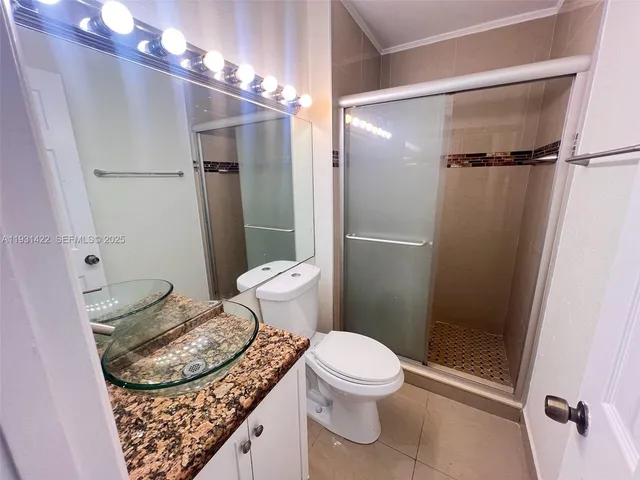 a bathroom with a granite countertop sink toilet and shower