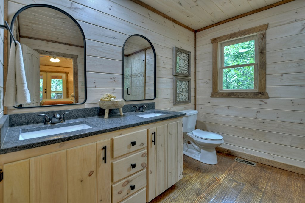 135 Windy Valley Lane Blue Ridge, GA 30513 - Photo 23 of 63 a bathroom with a granite countertop toilet a sink and a mirror