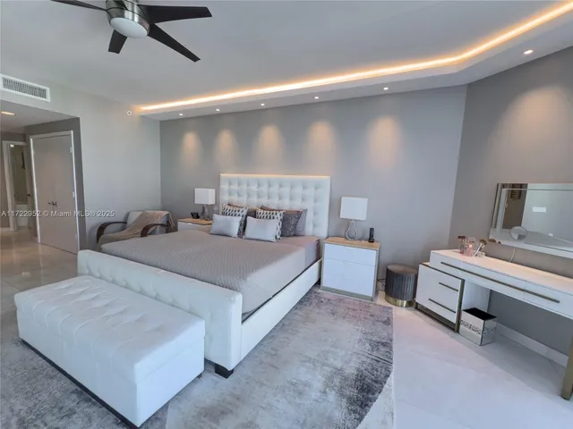 a spacious bedroom with a large bed and a chandelier