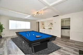 wooden floor with pool table and window