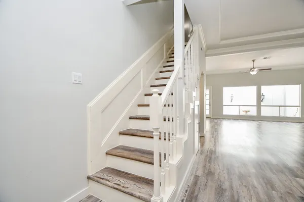 a view of a livingroom with a ceiling fan wooden floor and staircase