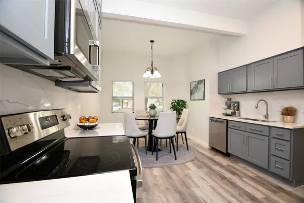 a kitchen with stainless steel appliances kitchen island granite countertop a sink dishwasher a stove a dining table and chairs with wooden floor