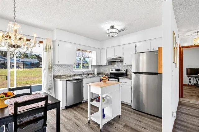 a kitchen with a refrigerator a stove a sink dishwasher and white cabinets with wooden floor