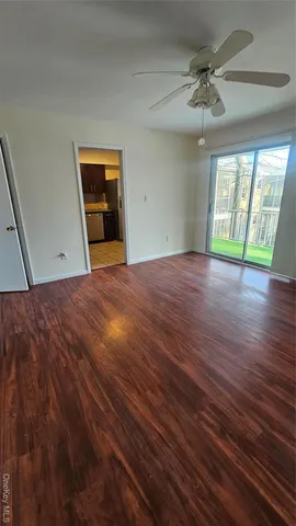 a view of an empty room with a window and wooden floor