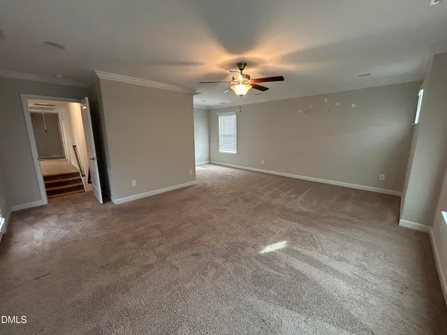 an empty room with chandelier fan and windows