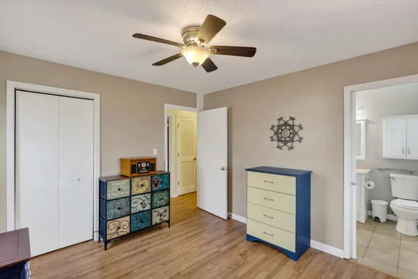 an empty room with wooden floor closet and windows