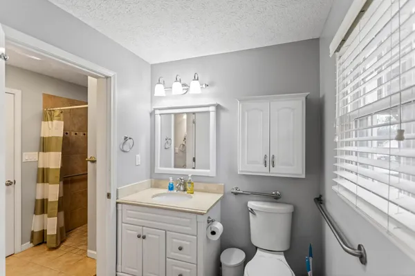 a bathroom with a toilet a sink a mirror a window and vanity